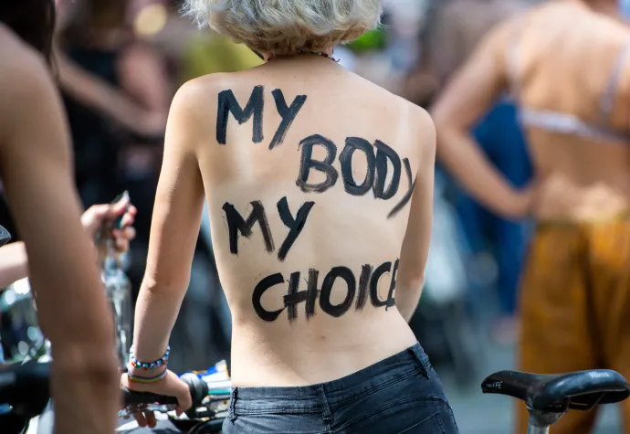 Az „Egy mellbimbó sem szabad, amíg minden mellbimbó nem az!" mottójú topless bringás tüntetés Berlinben 2021. július 10-én. A tiltakozást azért szervezték, mert korábban a rendőrség fellépett egy közparkban felső nélkül napozó nő ellen. Az egyik résztvevő testén az „Az én testem, az én választásom" felirat olvasható – Fotó: Christophe Gateau / Getty Images
