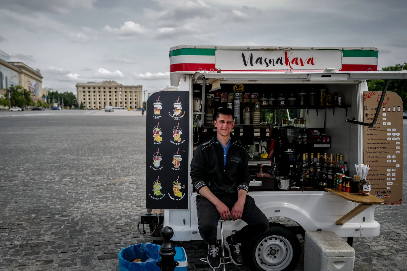 Kávéárus Harkiv központjában, a Szabadság téren (Majdan Szvobodi), háttérben a szétlőtt megyeházával – Fotó: Huszti István / Telex