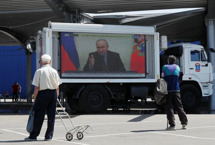 Valgyimir Putyin beszél egy orosz tévécsatornán, amit óriáskivetítőn néznek a helyiek Mariupol egyik segélyosztó pontján – Fotó: Alexander Ermochenko / Reuters