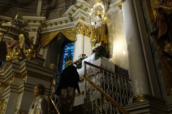 Hívő látogat el a csíksomlyói Mária-szoborhoz; hálatáblák a szobor melletti részen – Fotó: Molnár Réka / Telex.hu