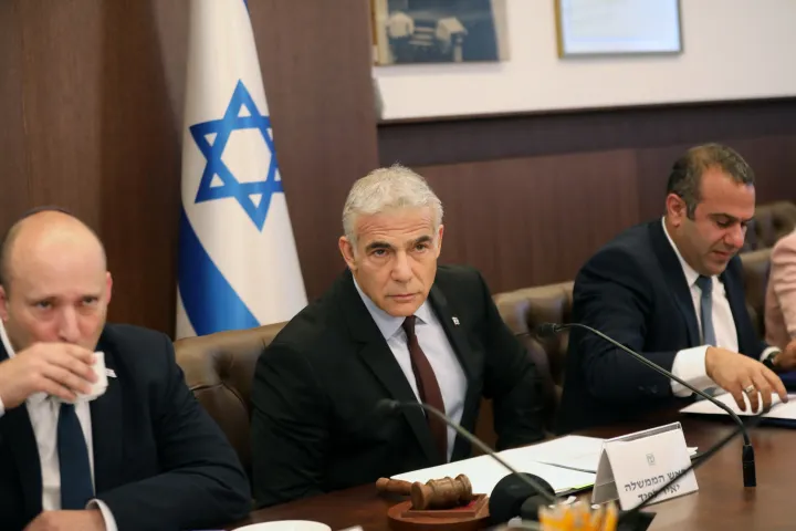 Naftali Bennett volt izraeli miniszterelnök, Jaír Lapid ügyvezető miniszterelnök, és Shalom Shlomo kabinetfőnök részt vesznek a kabinet első ülésén Jeruzsálemben 2022. július 3-án – Fotó: GIL COHEN-MAGEN / POOL / AFP