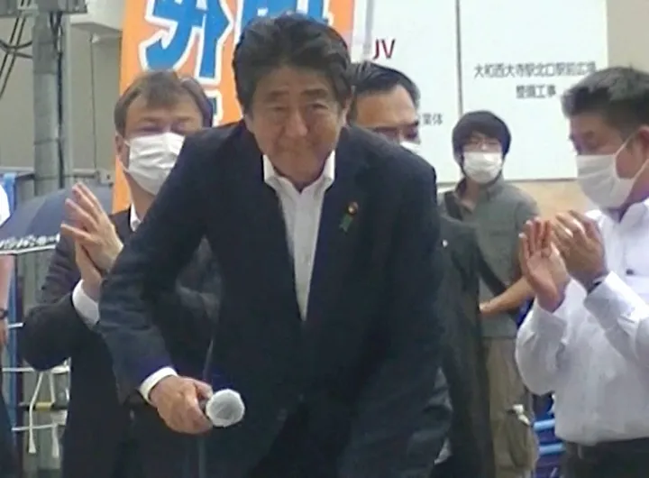Abe Shinzó nem sokkal azelőtt, hogy a héttérben álló, szürke inges Jamagami Tecuja hátba lőtte – Fotó: Mainichi Shimbun / Reuters