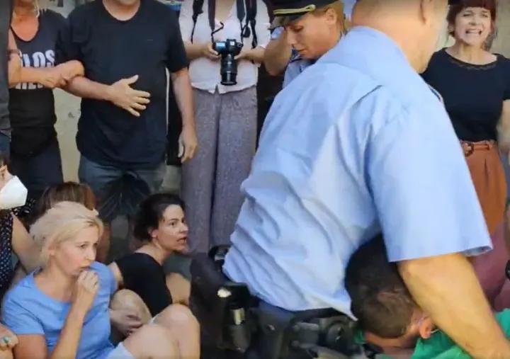 A rendőrök elviszik a sokkolt aktivistát – Forrás: Mérce / Facebook