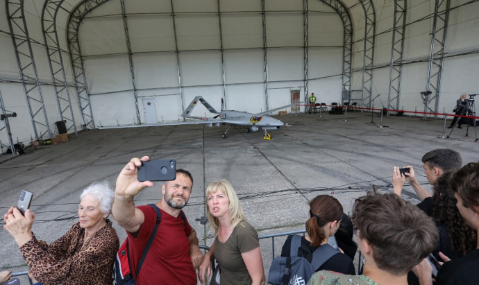 People take selfies with a Turkish Bayraktar TB2 combat drone, during its presentation at the Lithuanian Air Force Base in Siauliai, Lithuania, on July 6, 2022. – Lithuania on July 6, 2022 exhibited a crowdfunded Turkish-made military drone that it plans to send to Ukraine to help the war-torn country fight Russia's invasion. People in the NATO member country raised 5.9 million euros for the Bayraktar TB2 drone over three days last month, before its Turkish manufacturer Baykar announced it would donate the drone free of charge. (Photo by PETRAS MALUKAS / AFP)
