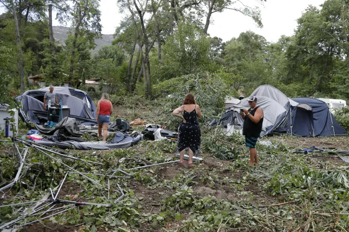A korzikai Sagone kempingben emberek szedik össze megmaradt holmijaikat és sátraikat. A kempingben egy fa egy bungalóra dőlt, és egy embert megölt 2022. augusztus 18-án – Fotó: Pascal Pochard-Casabianca / AFP 