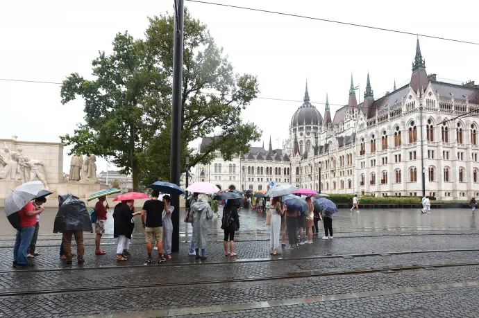 Az augusztus 20-i nemzeti ünnep alkalmából rendezett nyílt napra érkező látogatók állnak sorban esernyőket tartva az Országház előtt – Fotó: Kovács Anikó / MTI