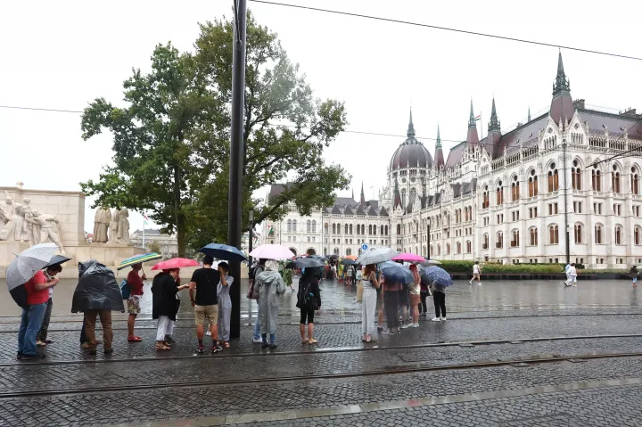 A nemzeti ünnep alkalmából rendezett nyílt napra érkező látogatók állnak sorban esernyőket tartva az Országház előtt 2022. augusztus 20-án – Fotó: Kovács Anikó / MTVA