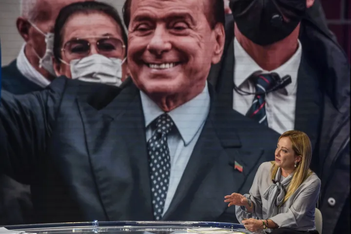 Giorgia Meloni beszél a Rai Uno csatorna Porta a Porta című televíziós talk show-jában, a háttérben Silvio Berlusconi a kivetítőn – Fotó: Antonio Masiello / Getty Images