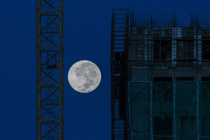 The moon is seen near a construction site in Kuala Lumpur on December 13, 2019. (Photo by Mohd RASFAN / AFP)