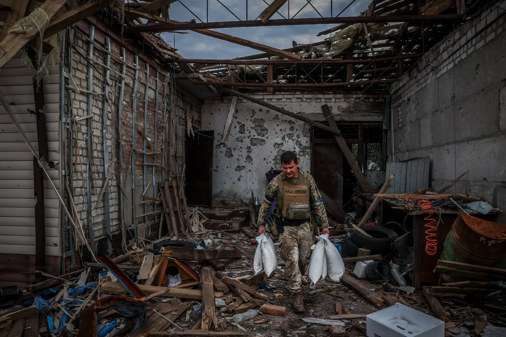 Az orosz megszállók által felhalmozott készletekből lisztet visz osztásra egy ukrán katona a raktár romjaiból – Fotó: Huszti István / Telex