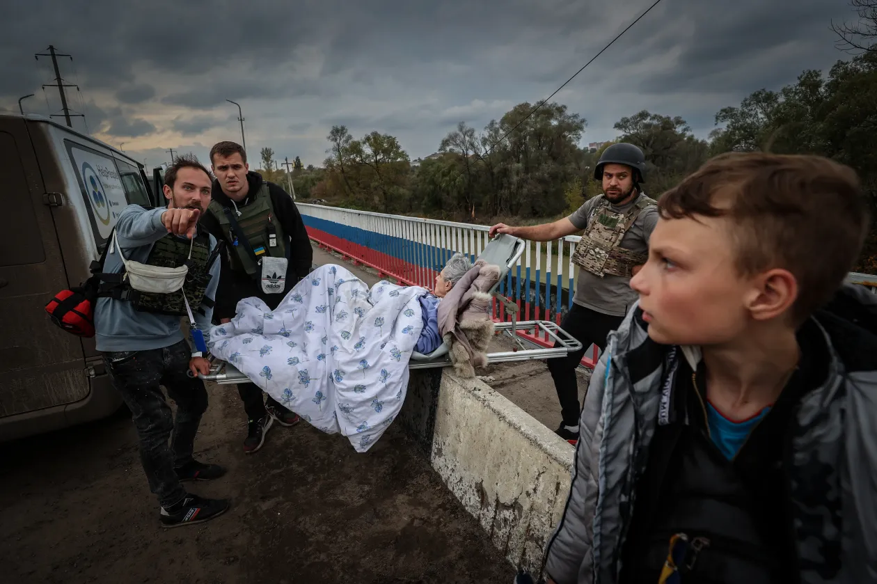 Menekülteket segítenek át az egyetlen útvonalon Ukrajna biztonságosabb része felé, az Oszkil folyó félig berobbant hídján, amelyen csak gyalogosan, legfeljebb motorral lehet átkelni – Fotó: Huszti István / Telex