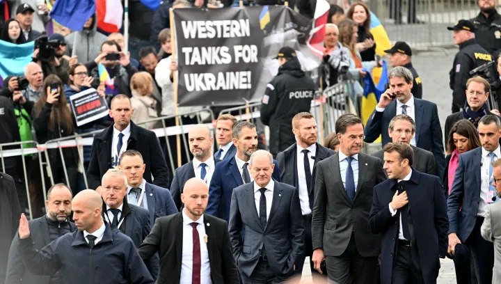 Emmanuel Macron francia elnök, Mark Rutte holland miniszterelnök és Olaf Scholz német kancellár érkeznek az EU informális csúcstalálkozójára, Prágába, 2022. október 7-én, „Nyugati tankokat Ukrajnának!” transzparenst tartó tüntetők mellett – Fotó: Joe Klamar / AFP