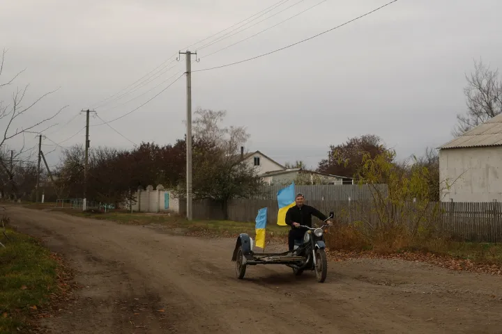 Jurij Nyevolcsuk tanár hazája zászlajával motorozik Blahodatne faluban, amelyet az ukrán csapatok egy napja foglaltak vissza az ukrajnai Herszon régióban, 2022. november 11-én. Fotó: Valentyn Ogirenko / Reuters