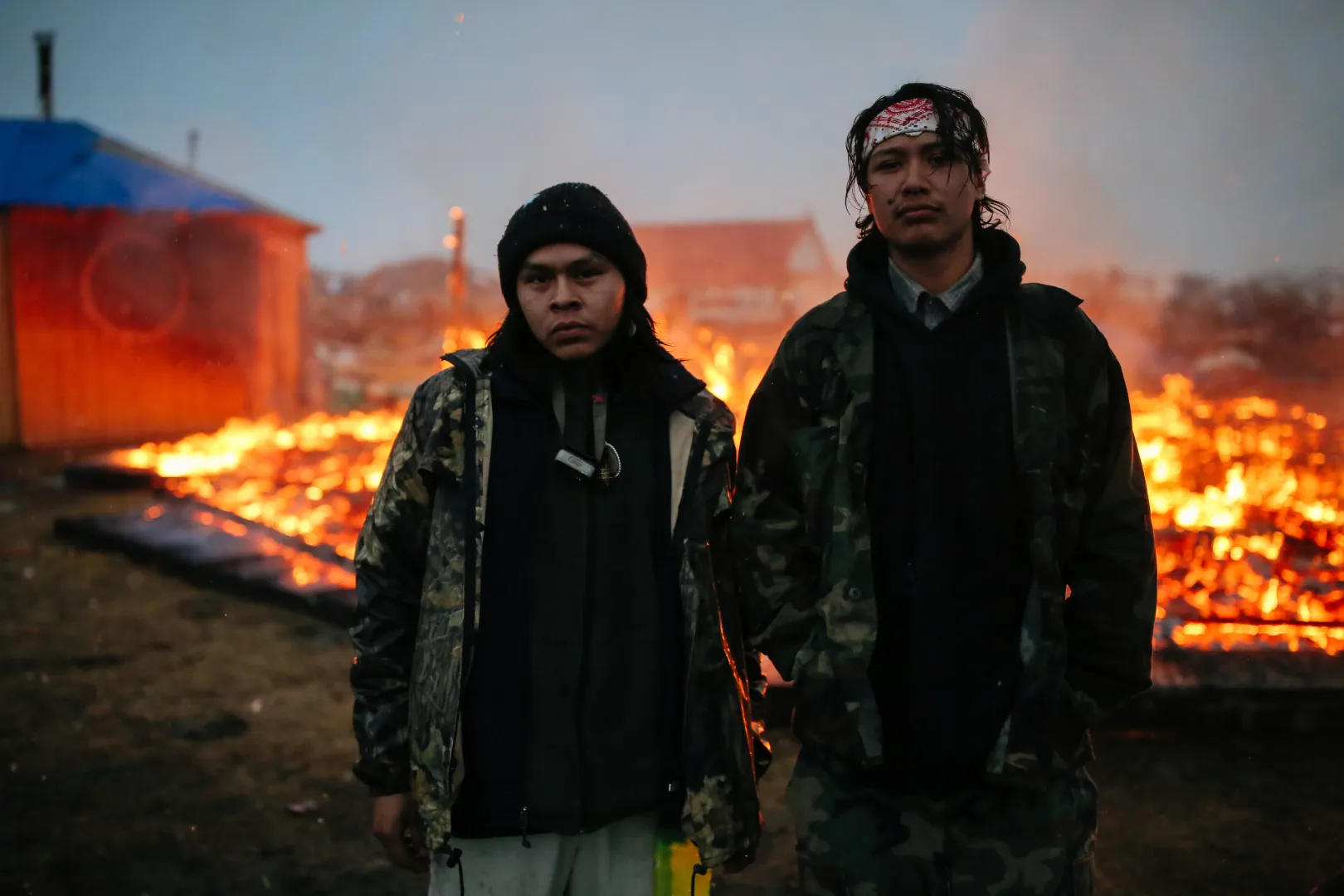 Két aktivista áll az észak-dakotai Cannon Ballban egy hagyományos navahó lakóház leégett maradványai előtt. A tiltakozók hónapokig demonstráltak az Álló Szikla rezervátum közelében futó Dakota Access olajvezeték megépítése ellen, és amikor 2017. február 22-én a hadsereg távozásra kényszerítette őket, a csoport egy része felgyújtotta az építményeket – Fotó: Stephen Yang / Getty Images 