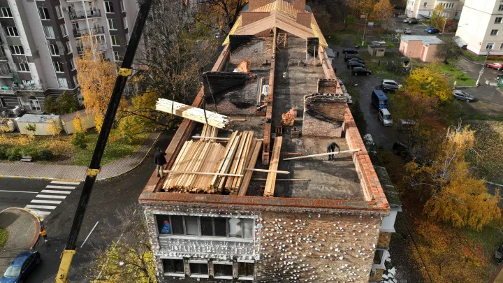 Építőmunkások javítják egy megrongálódott bucsai társasház tetejét – Fotó: Paula Bronstein / Getty Images
