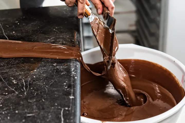 Templado de chocolate, que consiste en esparcir chocolate sobre una superficie de mármol, bajando así gradualmente su temperatura - Foto: Omar Torres / AFP