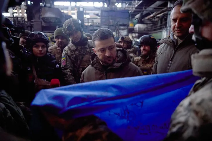 Bahmuti katonák átadnak egy aláírt ukrán zászlót Zelenszkijnek a városban tett keddi látogatásakor – Fotó: Stringer / AFP 