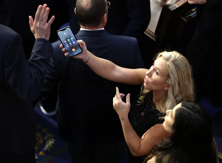Marjorie Taylor Greene próbálja odaadni telefonját a lázadó Matt Rosendale-nek. A vonalban „DT" – Fotó: Chip Somodevilla / Getty Images via AFP