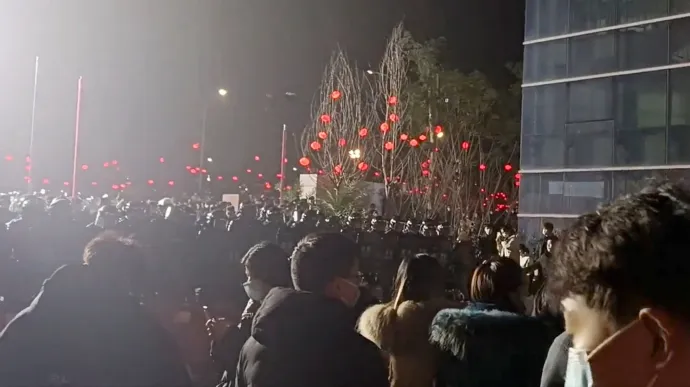 Tiltakozó dolgozók és a rohamrendőrök sorfala a kínai tesztgyár előtt 2023. január 7-én – Fotó: Video Obtained By Reuters