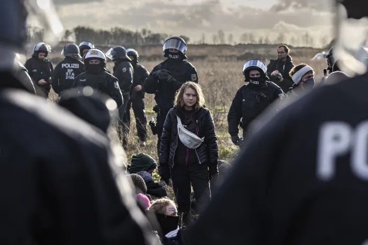 Rendőrök és felemelt kézzel tüntető klímaaktivisták, valamint Greta Thunberg a lignitbánya szélén, háttérben egy szénkotróval – Fotó: Oliver Berg / dpa / AFP
