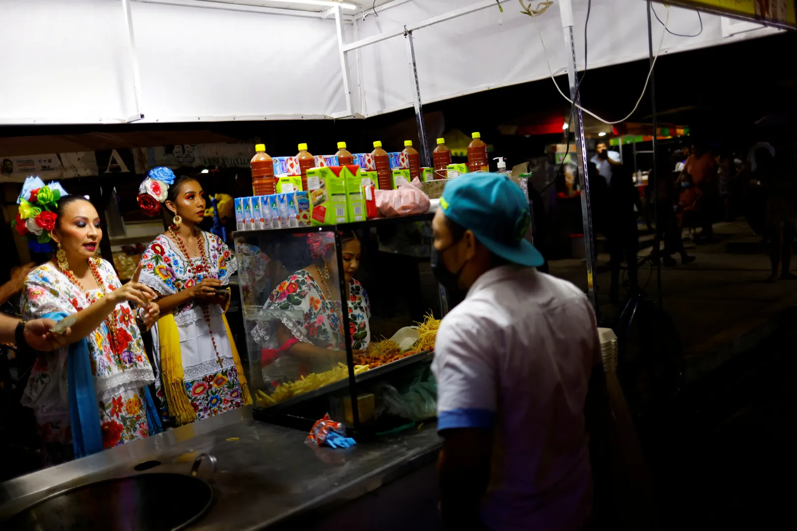 Népviseletbe öltözött nők rendelnek ételt egy rendezvényen egy vasút melletti településen – Fotó: Jose Luis Gonzalez / Reuters