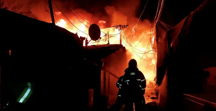 A gurjongi tűz megfékezésén dolgozó tűzoltók és a lángok martalékává lett nyomornegyed egy része – Fotó: Kim Hong-dzsi / Reuters / Yonhap News Agency