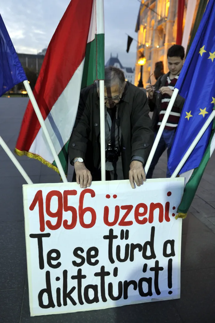 Mécs Imre, az Ötvenhatos Emlékbizottság elnöke, volt országgyűlési képviselő egy transzparenssel a Vissza a Forradalom lángját! címmel meghirdetett megemlékezésen A forradalom lángja emlékmű helyén, a Kossuth téren 2015. október 22-én – Fotó: Kovács Attila / MTI