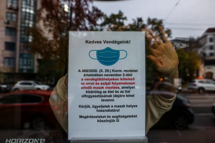 Egy budapesti kávézóban a kötelező maszkviselést előíró rendeletről szóló felhívást függesztik ki 2020 novemberében – Fotó: Huszti István / Telex