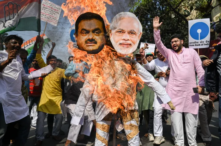 Indiai ellenzéki szimpatizánsok Gautam Adani és Narendra Modi miniszterelnök képét égetik egy tüntetésen 2023. február 6-án, mert a kormány állítólag nyomás alatt tartja az állami bankokat és biztosítókat, hogy azok Adani részvényekbe fektessenek – Fotó: Sankhadeep Banerjee / NurPhoto / Getty Images