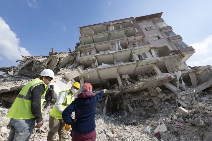 Egy nő a lerombolt háza előtt beszélget a segítőkkel a törökországi Antakiában – Fotó: Boris Roessler / Getty Images