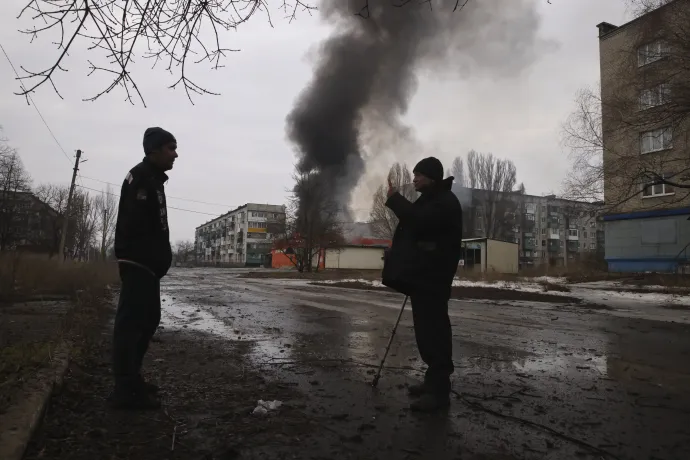 Égő ház előtt beszélget két férfi a kelet-ukrajnai Donyecki területen fekvő, az orosz hadsereg által ostromlott Bahmutban – Fotó: Jevhen Tyitov / MTI / AP 