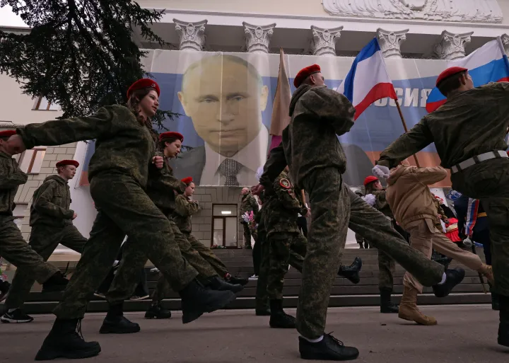 Orosz katonák Vlagyimir Putyin orosz elnök portréját ábrázoló molinó előtt vonulnak a Krím annektálásának kilencedik évfordulója alkalmából rendezett ünnepségen Jaltában, 2023. március 17-én – Fotó: Alexey Pavlishak / Reuters