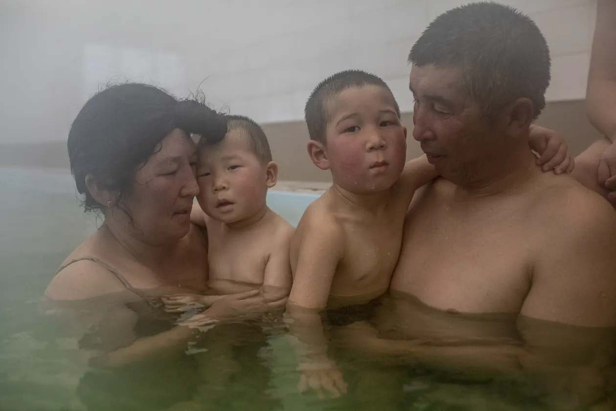 Dzsajnagul Brjieva és a családja egy melegvizes forrásnál a kirgizisztáni Kadzsi-Szajban 2021. március 9-én. A vízről úgy tartják, gyógyító hatása van. Az üledék vörösre festi az Amu-darja vízét, ahogy a vízszint növekszik