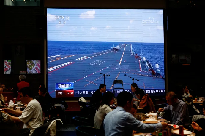 Egy pekingi étterem óriás kivetítőjén látható híradóban a kínai Shandong repülőgép-hordozóról a Tajvan körüli hadgyakorlat részeként felszálló repülőgépet mutatnak – Fotó: Tingshu Wang / Reuters