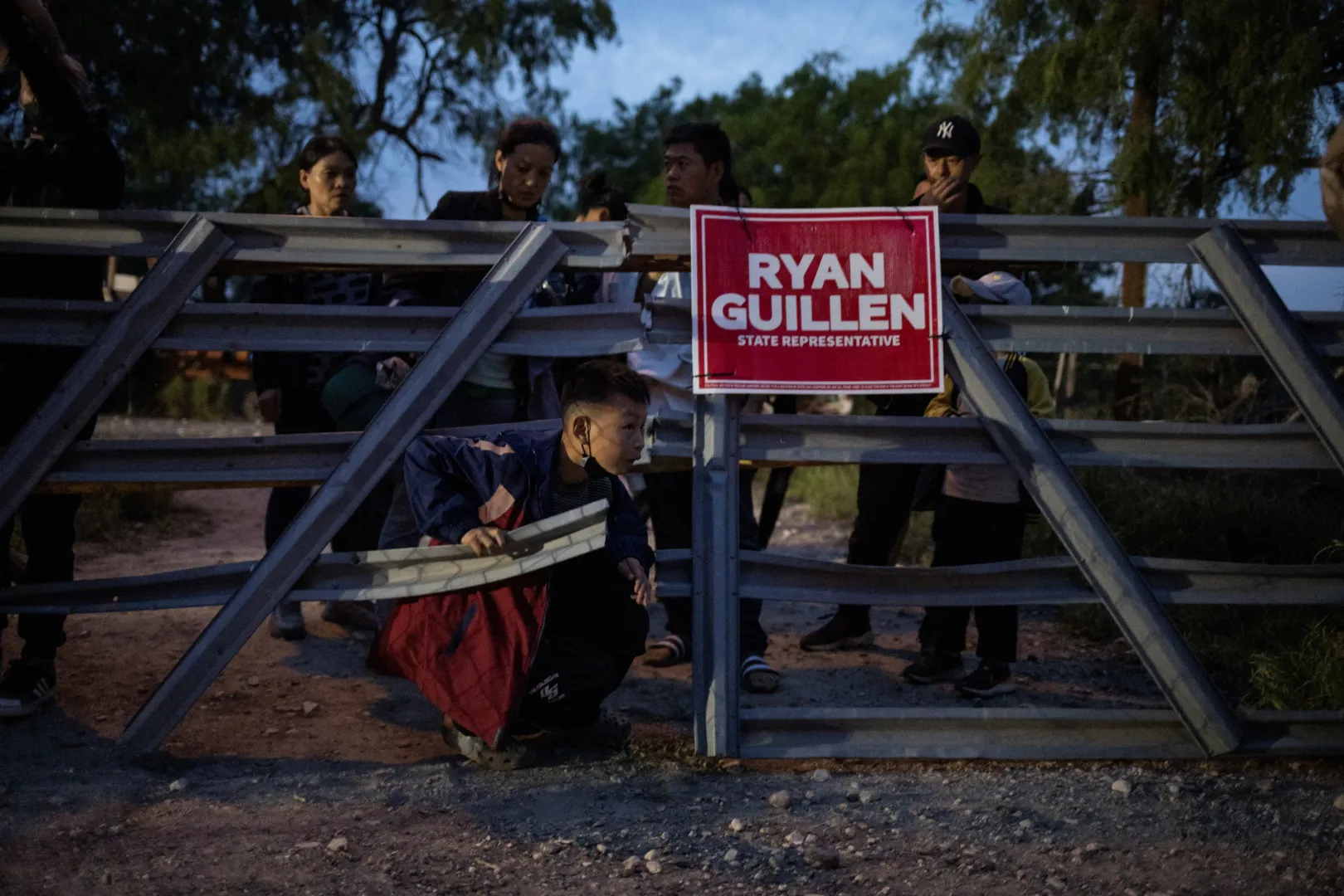 Fiatal bevándorló fiú bújik át egy kerítés alatt – Fotó: Reuters