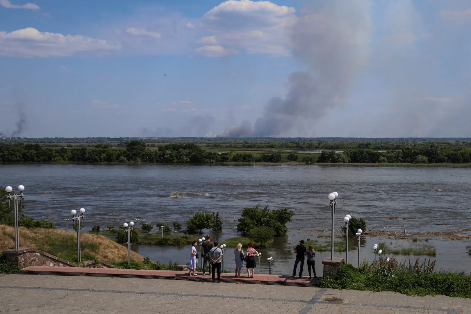 Helyi lakosok nézik az áradó Dnyepert a Nova Kahovka-i vízerőművet ellátó víztározó gátjának felrobbantása után – Fotó: Ivan Antypenko / Reuters
