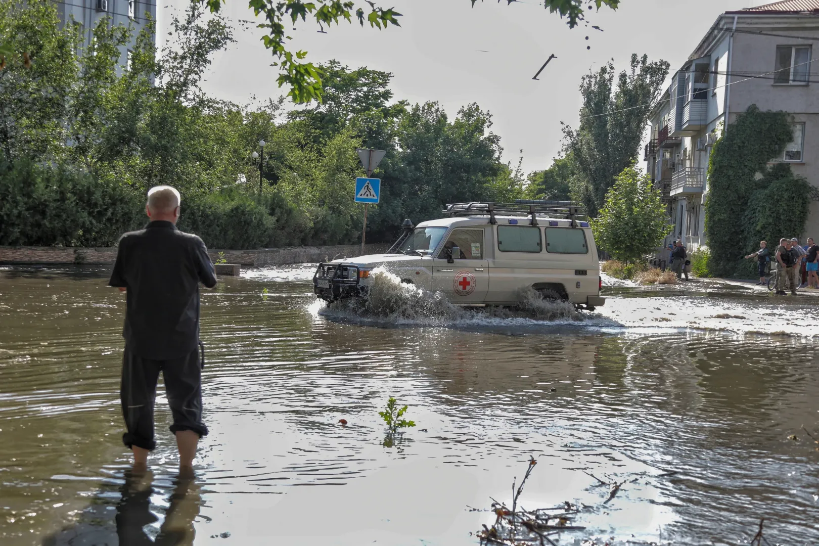 A Vöröskereszt önkénteseinek autója gázol a vízben Herszonban – Fotó: Reuters