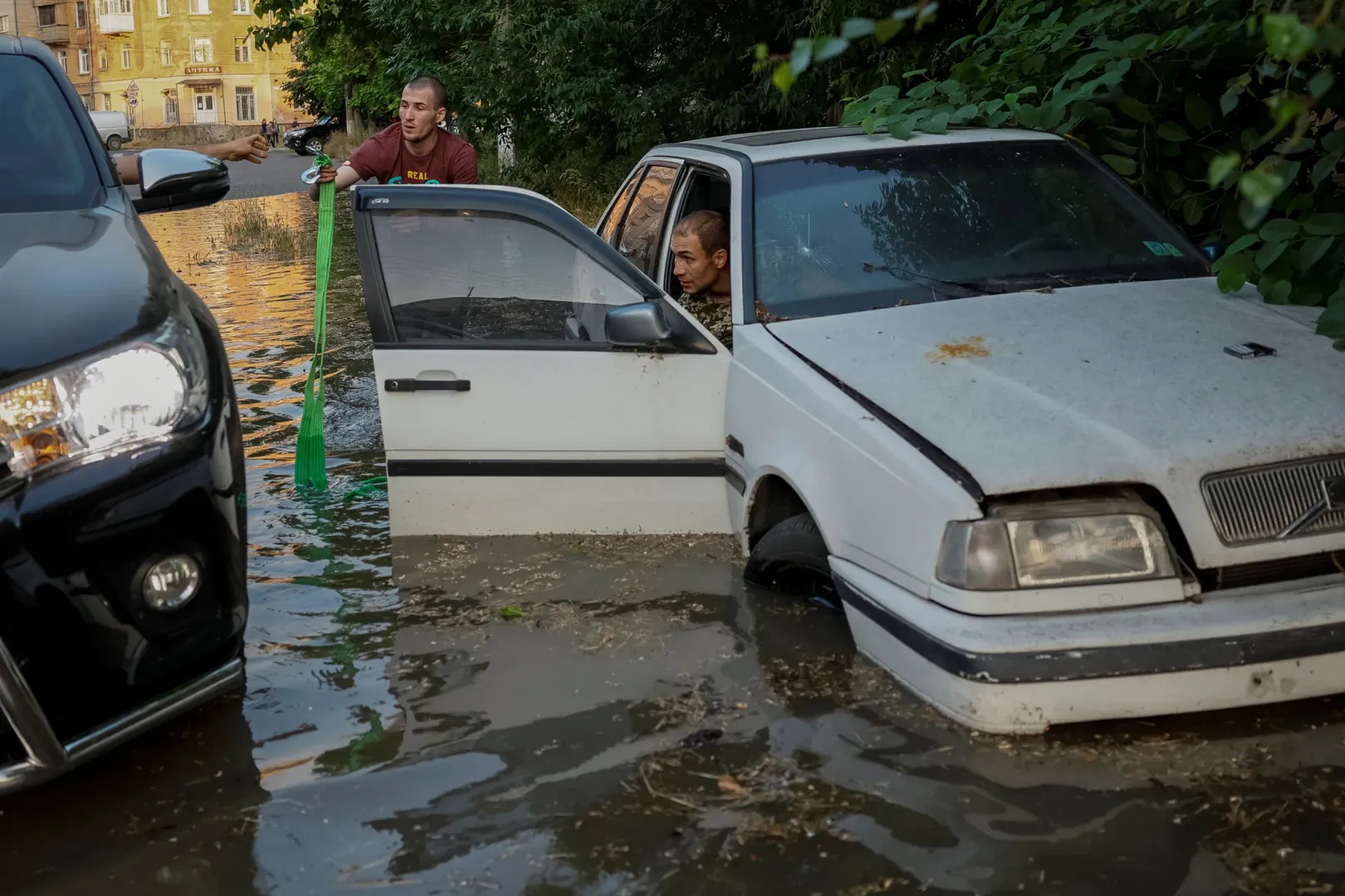 Egy vízben álló üzemképtelenné vált autót próbálnak meg kimenteni az utca elárasztott részéről Herszonban – Fotó: Alina Smutko / Reuters