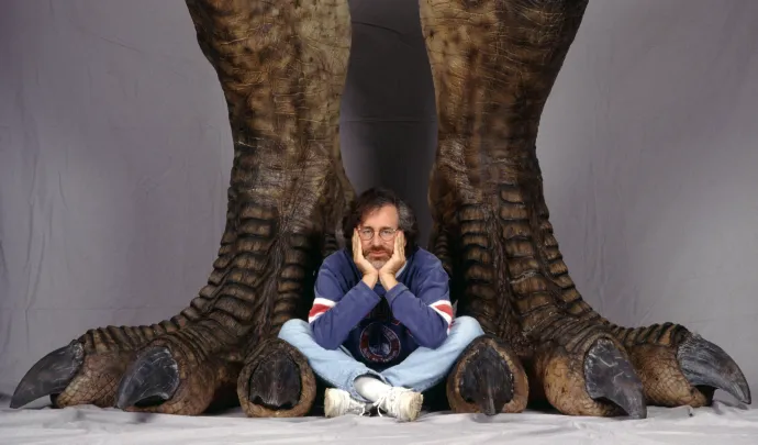 Steven Spielberg egy pár óriás dinoszauruszláb között pózol a Jurassic Park reklámfotóján, 1993-ban – Fotó: Murray Close / Getty Images
