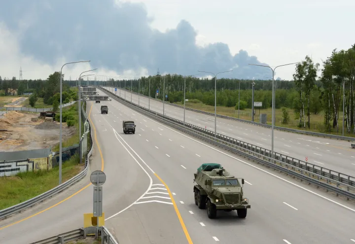 A Wagner-csoport katonai oszlopa halad az M4-es autópályán Moszkva felé 2023. június 24-én. A háttérben egy olajraktár égő üzemanyagtartályának füstje látható, az oroszországi Voronyezs közelében – Fotó: Stringer / Reuters