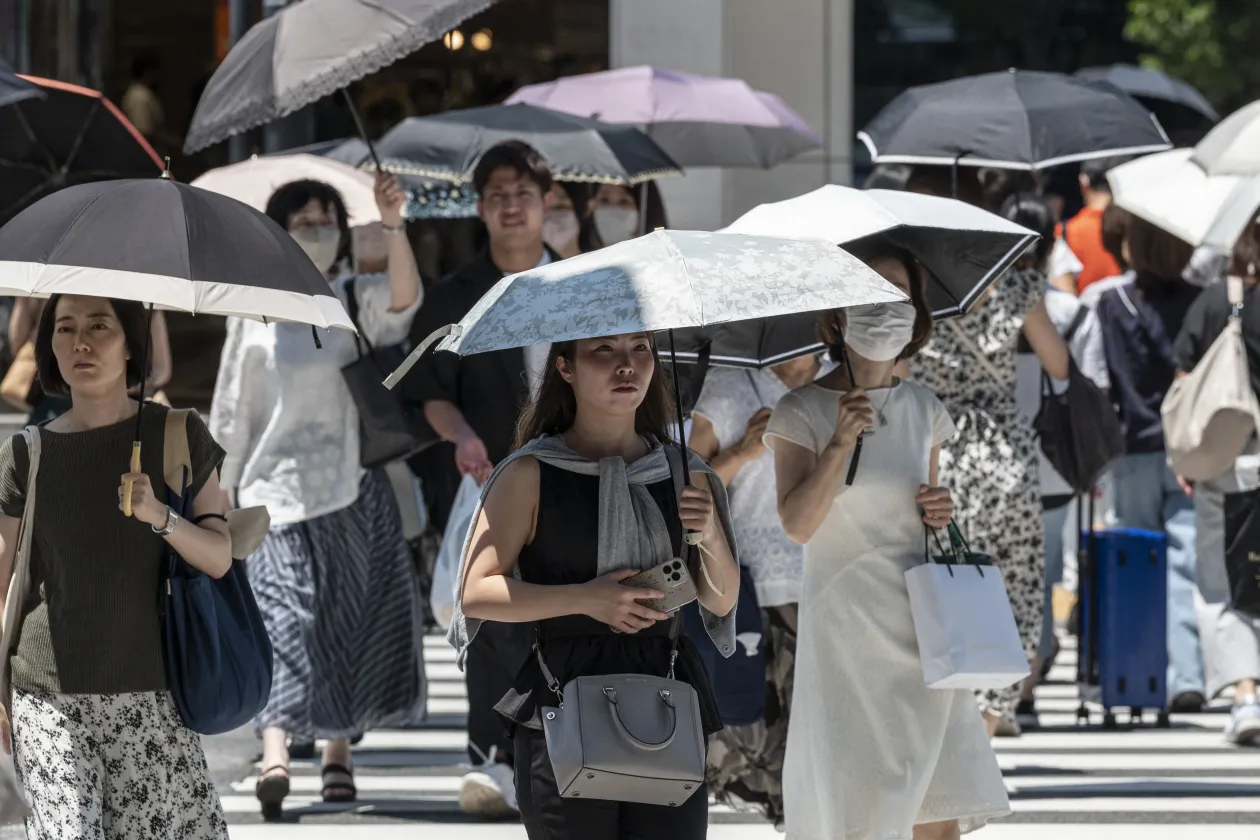 A gyalogosok esernyővel és maszkokkal védekeznek a déli napsütés ellen, miközben átkelnek az utcán Tokió belvárosában július 17-én – Fotó: Richard A. Brooks / AFP; Jade Gao / AFP
