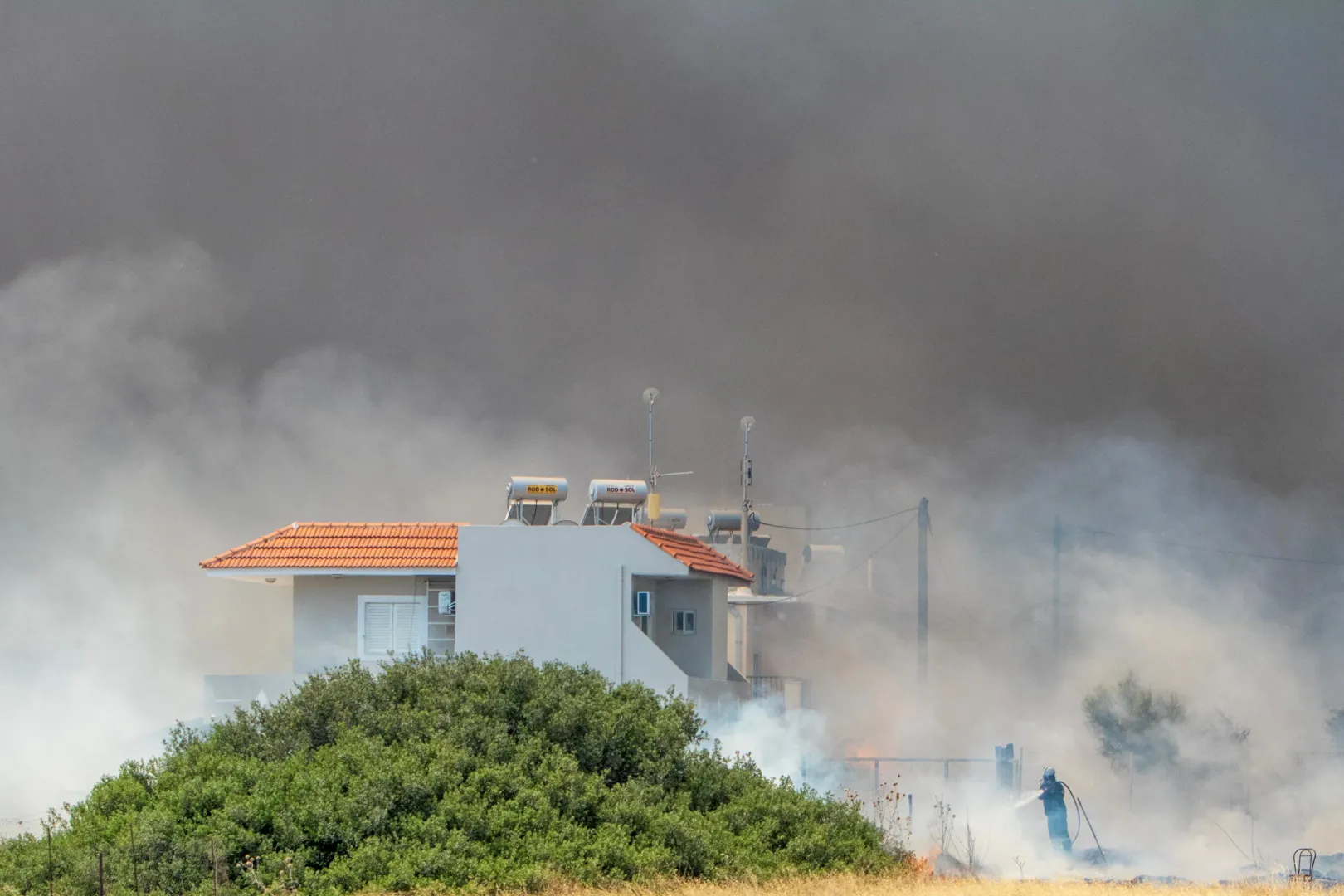 Tűzoltó próbál eloltani egy lángoló nyaralót Kiotari faluban, Rodosz szigetén 2023. július 24-én – Fotó: Lefteris Damianidis / Reuters