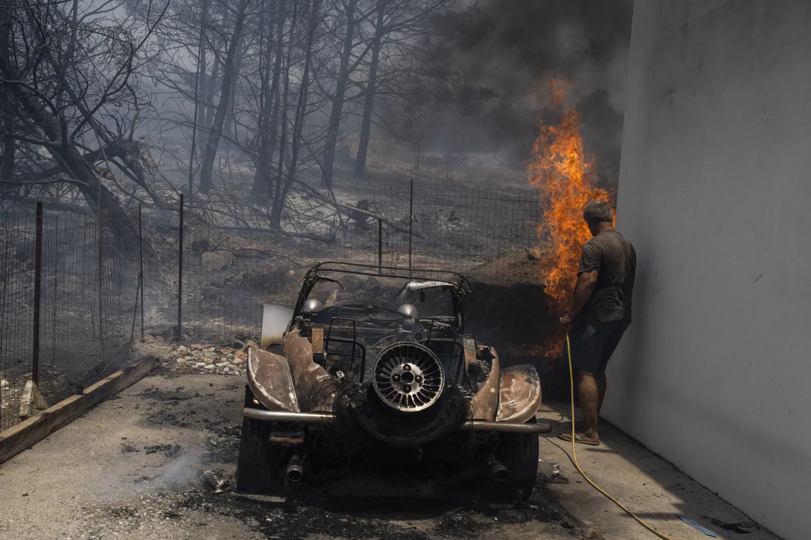 Egy helybeli férfi próbálja eloltani a lángokat egy magánház udvarán Rodoszon 2023. július 24-én – Fotó: Pétrosz Jannakurisz / AP / MTI
