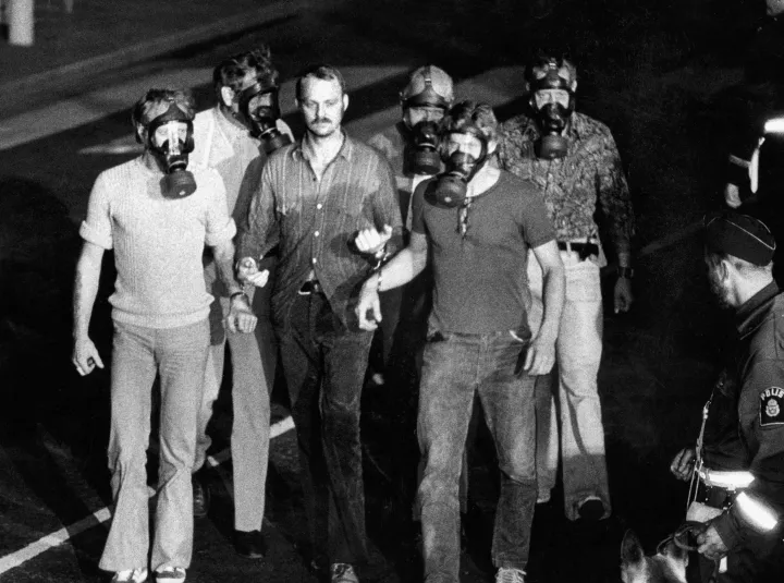 Öt gázálarcos rendőr kíséri Jan-Erik Olssont a Kreditbanken épületéből, 1973. augusztus 28-án – Fotó: Bent O NORDIN BON / TT NEWS AGENCY / AFP