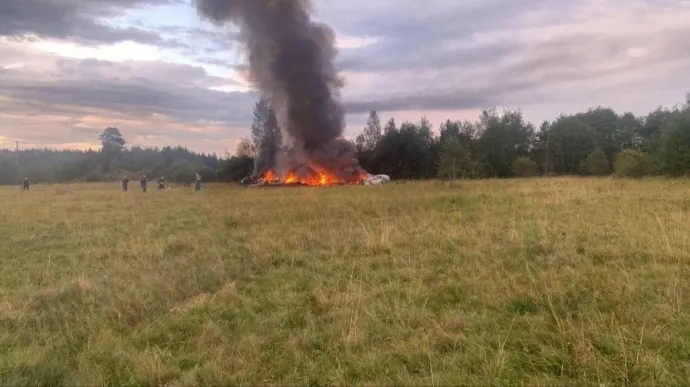Mentőalakulatok tagjai a Kuzsenkino község közelében lezuhant magánrepülőgép lángoló roncsa mellett 2023. augusztus 23-án – Fotó: Wagner Telegram Account / Anadolu Agency / AFP
