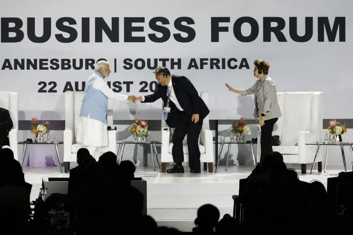 Narendra Modi indiai miniszterelnök és Vang Ventao kínai kereskedelmi miniszter kezet fog a BRICS-csúcson. Mellettük a színpadon Dilma Rousseff volt brazil elnök, az Új Fejlesztési Bank elnöke – Fotó: Marco Longari / AFP