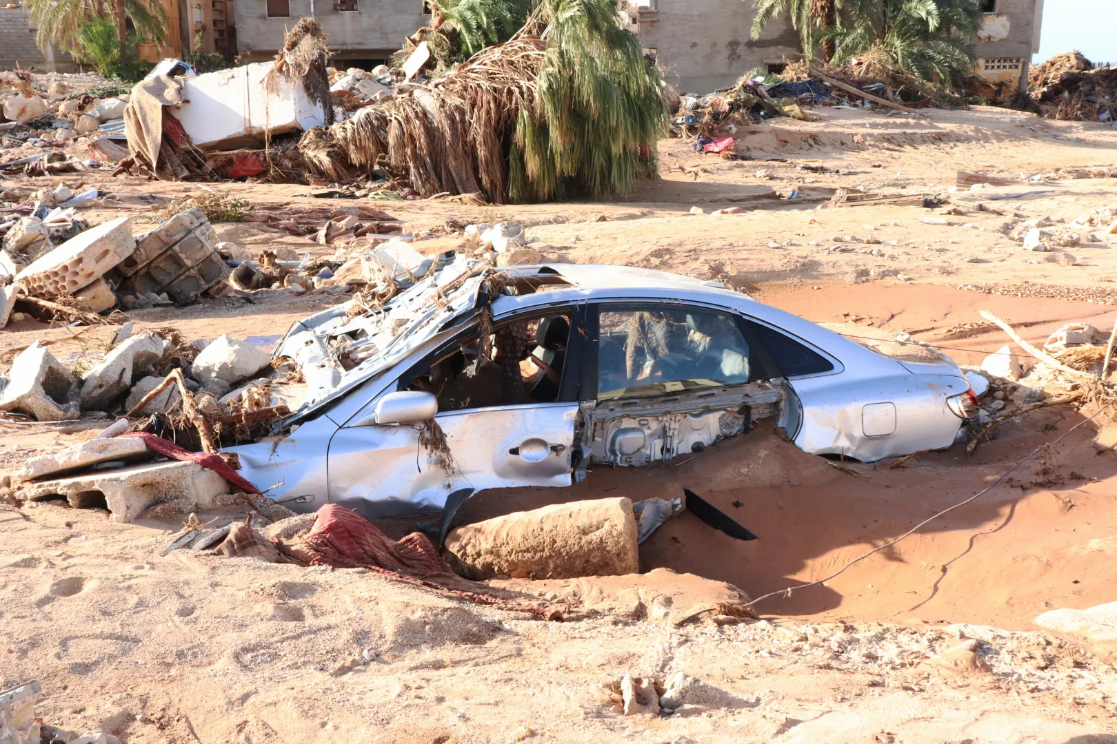Sárba süllyedt autó a romok között Dernában 2023. szeptember 12-én – Fotó: Abdullah Mohammed Bonja / Anadolu Agency / AFP