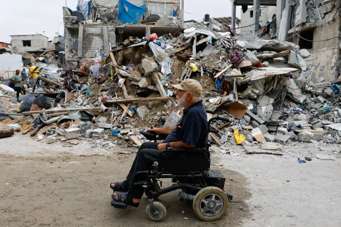 Egy kerekesszékes palesztin halad el az izraeli csapásokban lerombolt épületek romjai mellett a Gázai övezet déli részén fekvő Rafahban 2023. október 9-én – Fotó: Ibraheem Abu Mustafa / Reuters