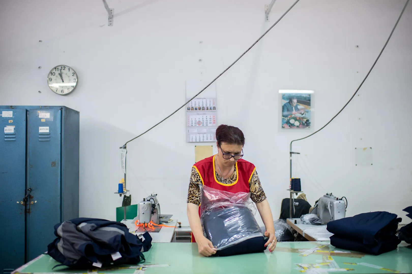 A worker packages clothes at the Željezničar company's sewing facility in Subotica. In the background on the wall hangs a portrait of Josip Broz Tito, former President of Yugoslavia – Photo by János Bődey / Telex