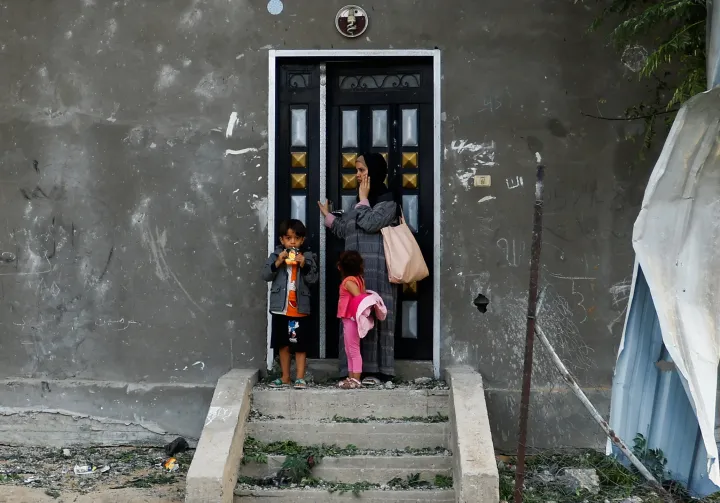 Egy palesztin nő áll a gyerekekkel egy megrongálódott ház ajtajánál az izraeli csapásokat követően a Gázai övezet déli részén fekvő Khan Júniszban 2023. október 11-én – Fotó: Ibraheem Abu Mustafa / Reuters